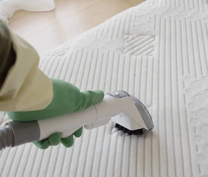 Steam cleaning brush sanitising a quilted mattress surface