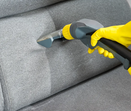 Close detail of an upholstery tool lifting dirt from sofa fabric