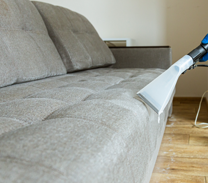 Upholstery extraction tool cleaning a grey fabric sofa